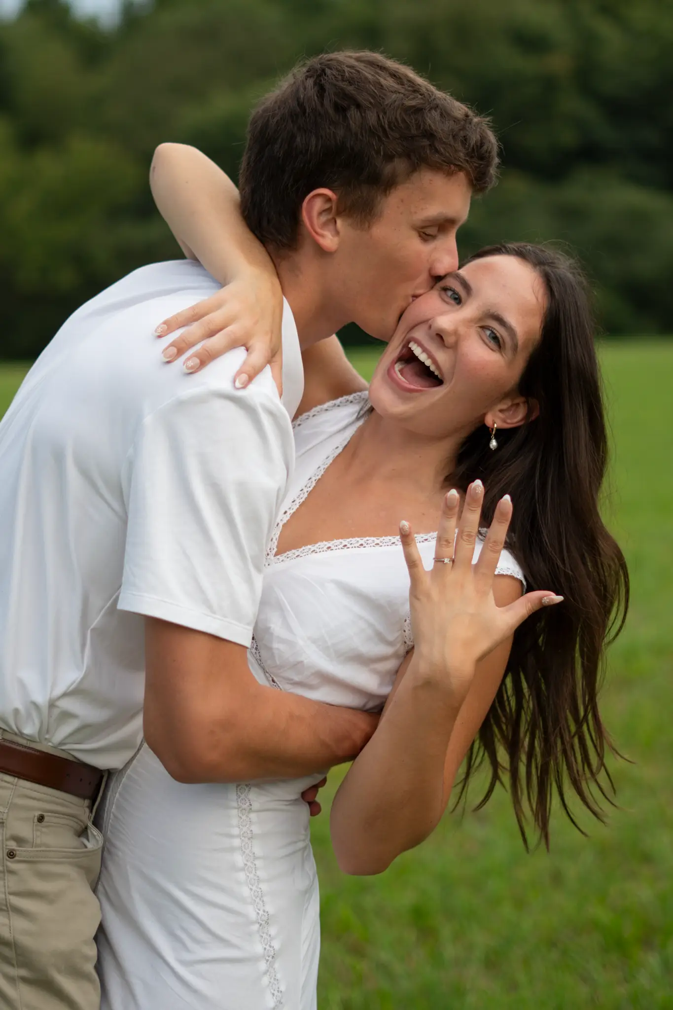 Isabella laughing and showing her engagement ring while Nathan holds her