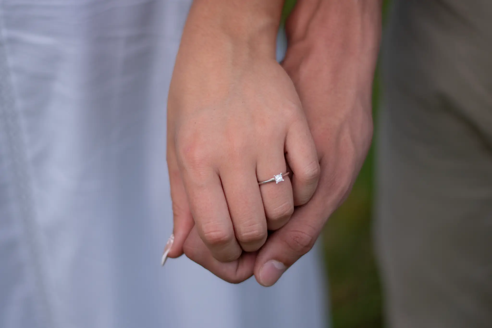 A close view of their joined hands, her engagement ring on show